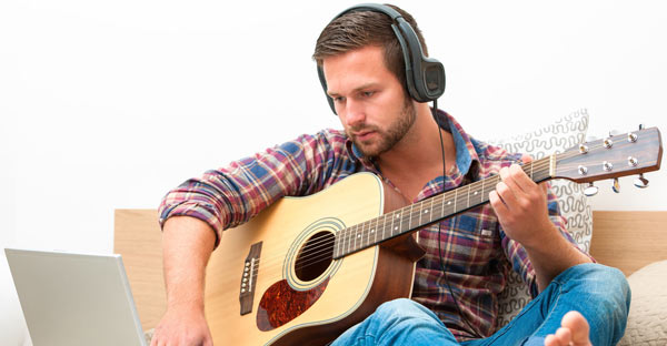 Man with headphones playing the guitar.